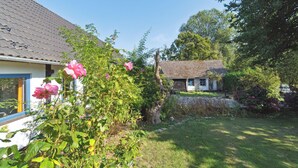 A house with a tiled roof, a garden with pink flowers, and a clear blue sky. - Cozy summer house on Bornholm (Nexø)