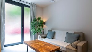 A modern living room with a sofa, a wooden coffee table, and a potted plant. - VLC HOST - Luz Casanova E (Valencia)