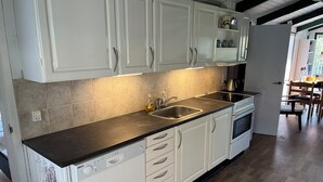 A kitchen with white cabinets, a black countertop, a stainless steel sink, and a dishwasher.