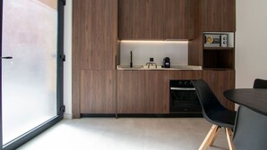 A modern kitchen with wooden cabinets, a built-in oven, and a dining area with a table and chairs. - VLC HOST - Luz Casanova B (Valencia)