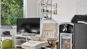 Una sala moderna con televisor de pantalla plana, sofá de cuero blanco, chimenea y estantería frente a una pared de ladrillo blanco.