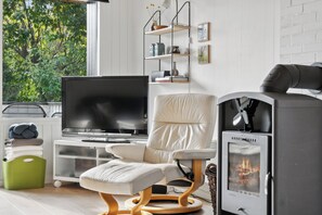 Ein modernes Wohnzimmer mit Flachbildfernseher, einem weißen Ledersofa, Kamin und einem Bücherregal an einer weißen Ziegelwand.