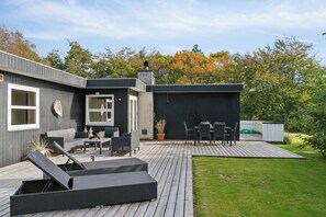 Moderni ulkoterrassi, jossa on istuimia, grillauspaikka ja katettu alue.