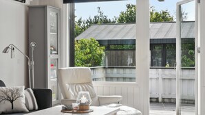 Un interior moderno con un sofá, una mesa con vela y vistas a una terraza exterior.