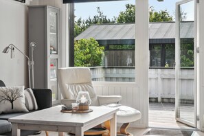 A modern interior with a sofa, a table with a candle, and a view of an outdoor deck.
