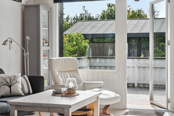 A modern interior with a sofa, a table with a candle, and a view of an outdoor deck.