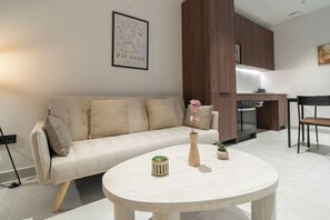 A modern living room with a beige sofa, a round coffee table, and a kitchen in the background.
