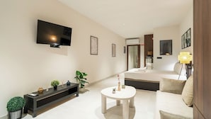 A modern living room with a flat-screen TV, a sofa, a round coffee table, and a console table with decorative items.