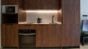 A modern kitchen with wooden cabinetry, a built-in microwave, a coffee machine, a sink, and an oven. - VLC HOST - Luz Casanova C (Valencia)