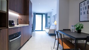 A modern kitchen with built-in appliances, a dining area with a table and chairs, and a view to a living room with a sofa and a plant. - VLC HOST - Luz Casanova C (Valencia)