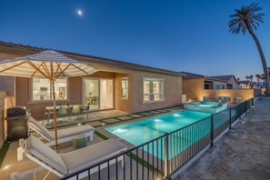 A residential property with a swimming pool, outdoor seating, and a patio area.