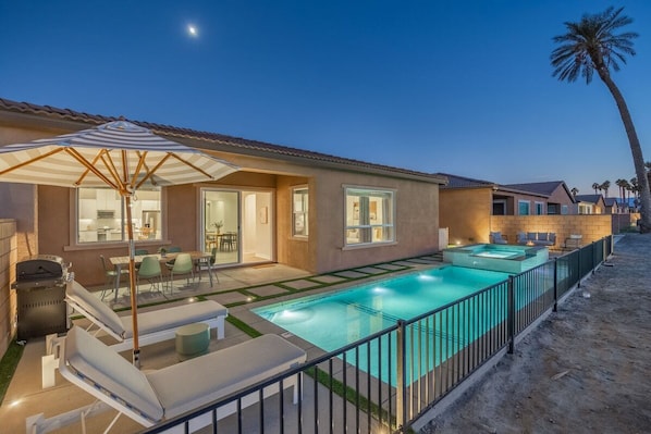 A residential property with a swimming pool, outdoor seating, and a patio area.