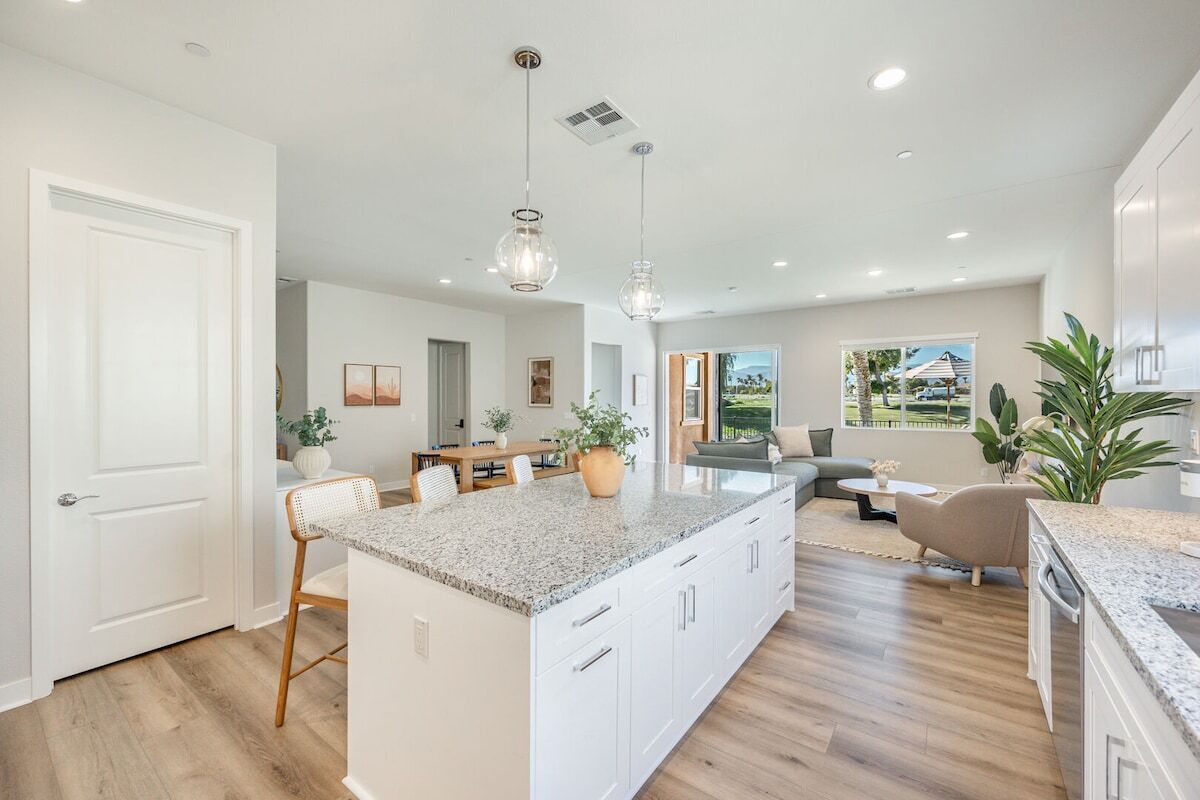 A spacious kitchen with a large island, wooden flooring, and pendant lighting.