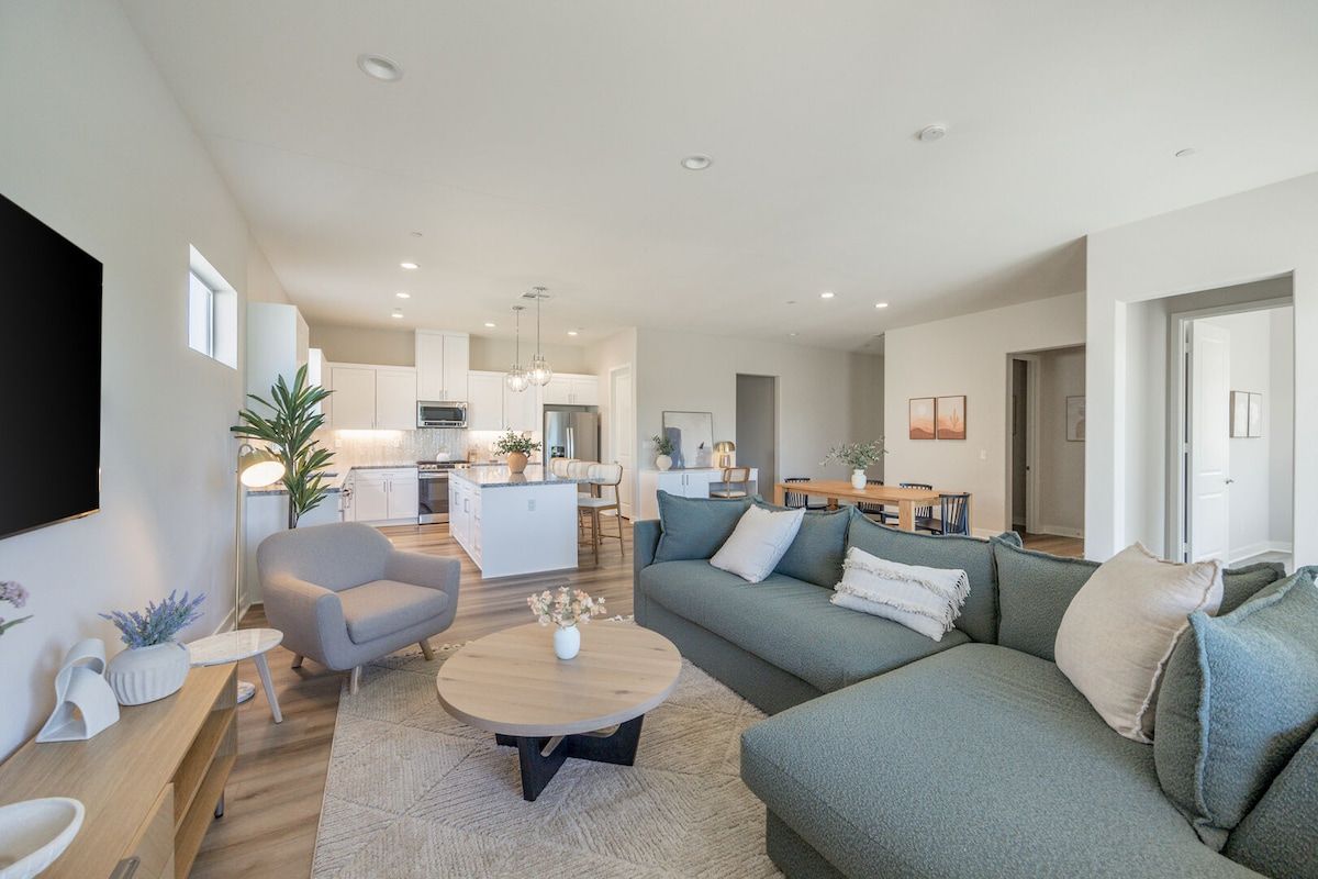 Un salon moderne avec un canapé, un fauteuil, une table basse et un téléviseur.