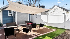 Un patio con mobiliario exterior y una vela de sombra.