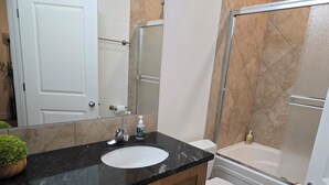 A bathroom with a black marble sink, a toilet, a shower, and a white door. - Kensington Area 10 Mins To Downtown! Clean and friendly! Temporary stays!  (Calgary)
