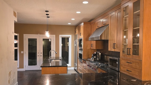 A spacious kitchen with wooden cabinets, a black countertop, and two stools. - Kensington Area 10 Mins To Downtown! Clean and friendly! Temporary stays!  (Calgary)