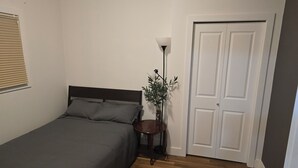 A bedroom with a bed, bedside table, lamp, and a door. - Kensington Area 10 Mins To Downtown! Clean and friendly! Temporary stays!  (Calgary)