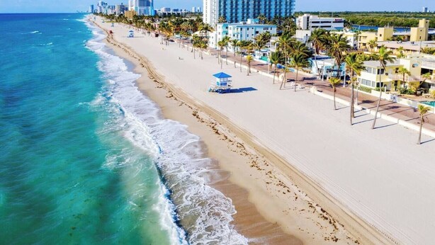 A coastal hotel with a beachfront view, a pool area, and a lifeguard tower.