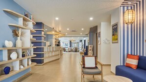 Una hall moderna di un hotel con scaffali in legno, un’area salotto e una reception.