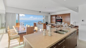 A modern kitchen with a built-in Netflix screen, a dining area with a view of the sea, and a spacious living area. - Luxury Beach Front Condo  21st Floor Views (Puerto Vallarta)