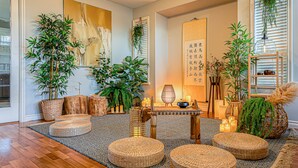 A room with a wooden floor, woven poufs, a table with candles, and various plants. - 180° Amazing View- Ridge Top, 2 Full Kitchen, 3-Level, Sleeps 16 Comfortably (Chilliwack)