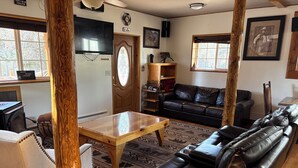 A cozy living room with a wooden coffee table, leather sofa, and a television.