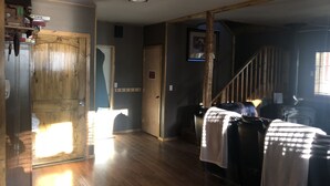 A spacious room with wooden flooring, a staircase, and a door with a 'KEEP OUT' sign.