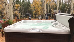A hot tub on a wooden deck with a view of a forested area.