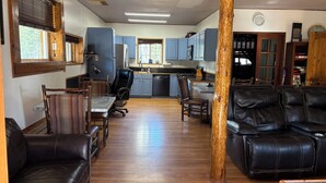 A spacious living area with a dining table, leather sofas, and a kitchen in the background.