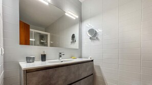 A modern bathroom with a large mirror, a sink, and a vanity.