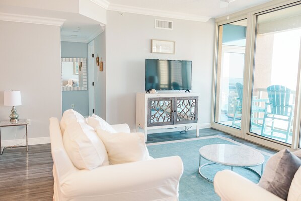 A modern living room with a white sofa, a round coffee table, and a TV on a cabinet.