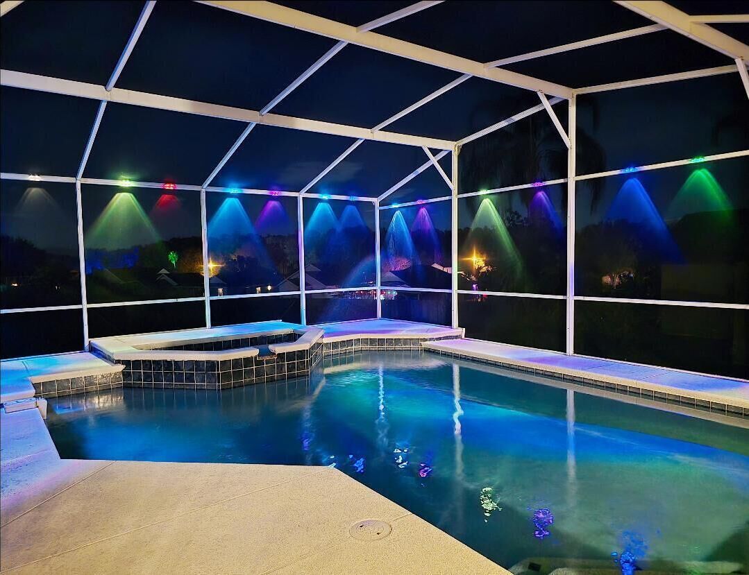 Une piscine intérieure dotée d’une paroi vitrée et éclairée par des jeux de lumière colorés.