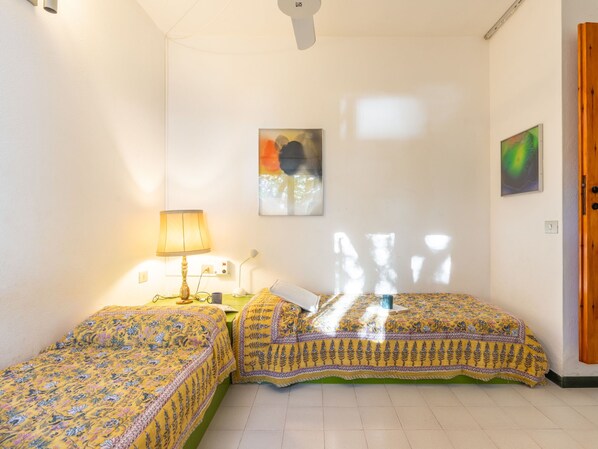 Una habitación con dos camas, una lámpara, un cuadro y una puerta.