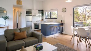 A modern kitchen with white cabinets, a built-in oven, and a large window. - Gumleaf - Freycinet Holiday Houses (Coles Bay)