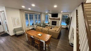 A spacious living room with a wooden dining table, sofas, and a fireplace.