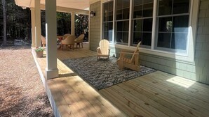 A covered porch with wooden flooring, large windows, and outdoor seating.