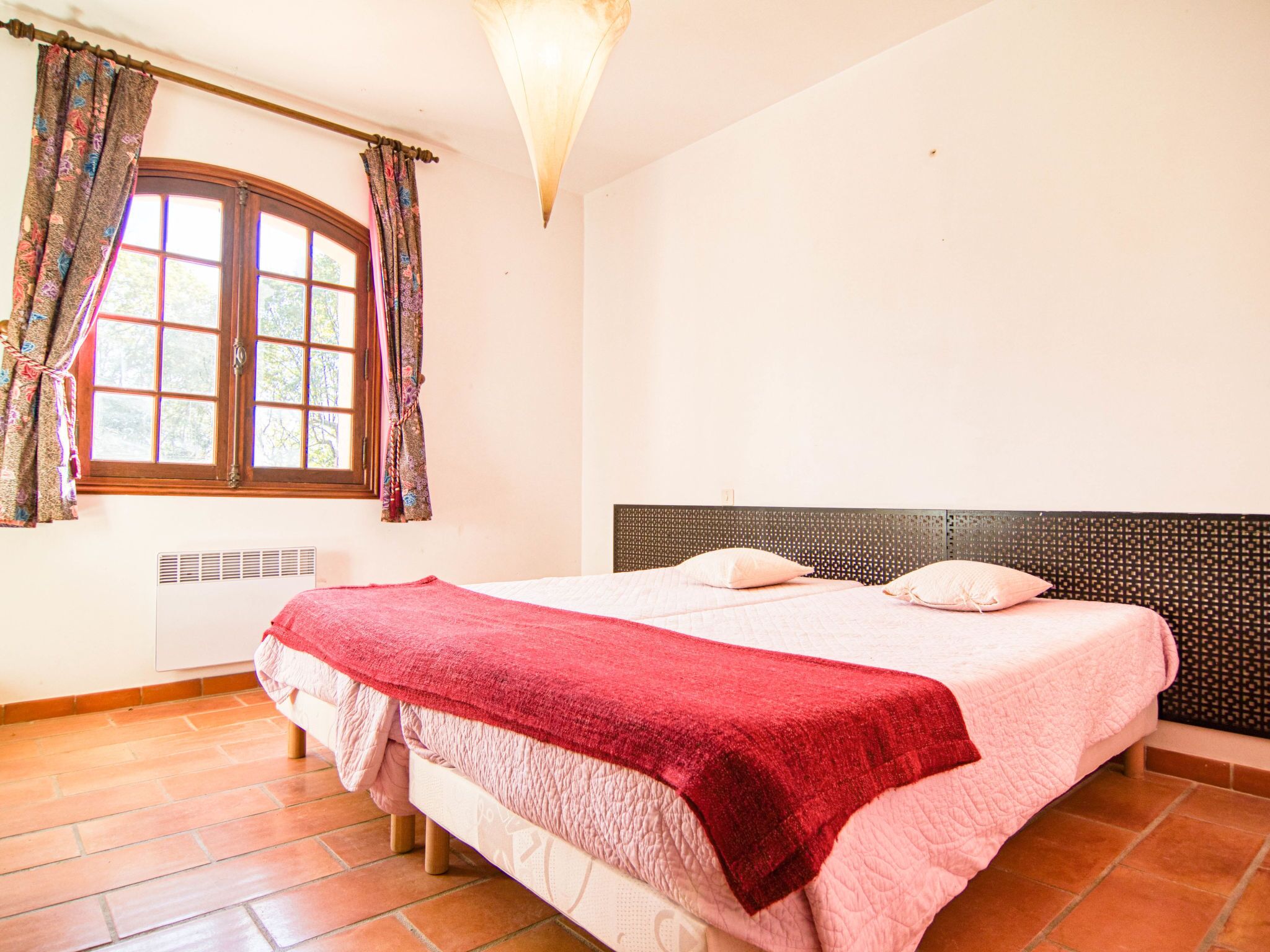 A bedroom with a bed, curtains, a window, and a headboard.