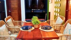 A dining area with a wooden table, wicker chairs, and a central plant. - Dockyard by Araw Residences (El Nido)