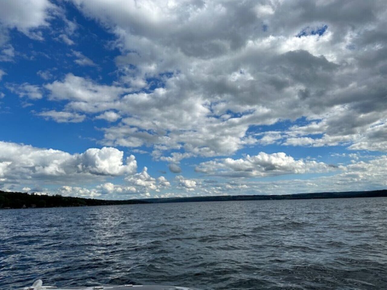 A view of a body of water with a distant shoreline and a partly cloudy sky.