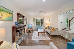 A living room with a fireplace, a television, a sofa, a coffee table, and a blue armchair.