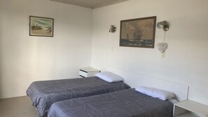 Una stanza con due letti, un comodino e due lampade a parete.