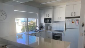 A modern kitchen with white cabinetry, a large island with stools, a microwave, oven, and refrigerator. - Spinnaker Seas Ocean Views | Walk to Kings Beach | Pool (Kings Beach)