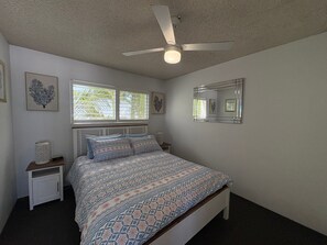 A bedroom with a bed, nightstands, a ceiling fan, a window with blinds, and a wall-mounted mirror. - Spinnaker Seas Ocean Views | Walk to Kings Beach | Pool (Kings Beach)
