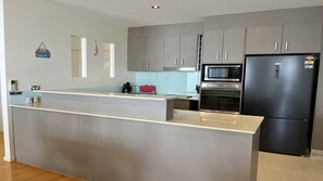 Una cocina moderna con gabinetes grises, un refrigerador de acero inoxidable y un microondas integrado.