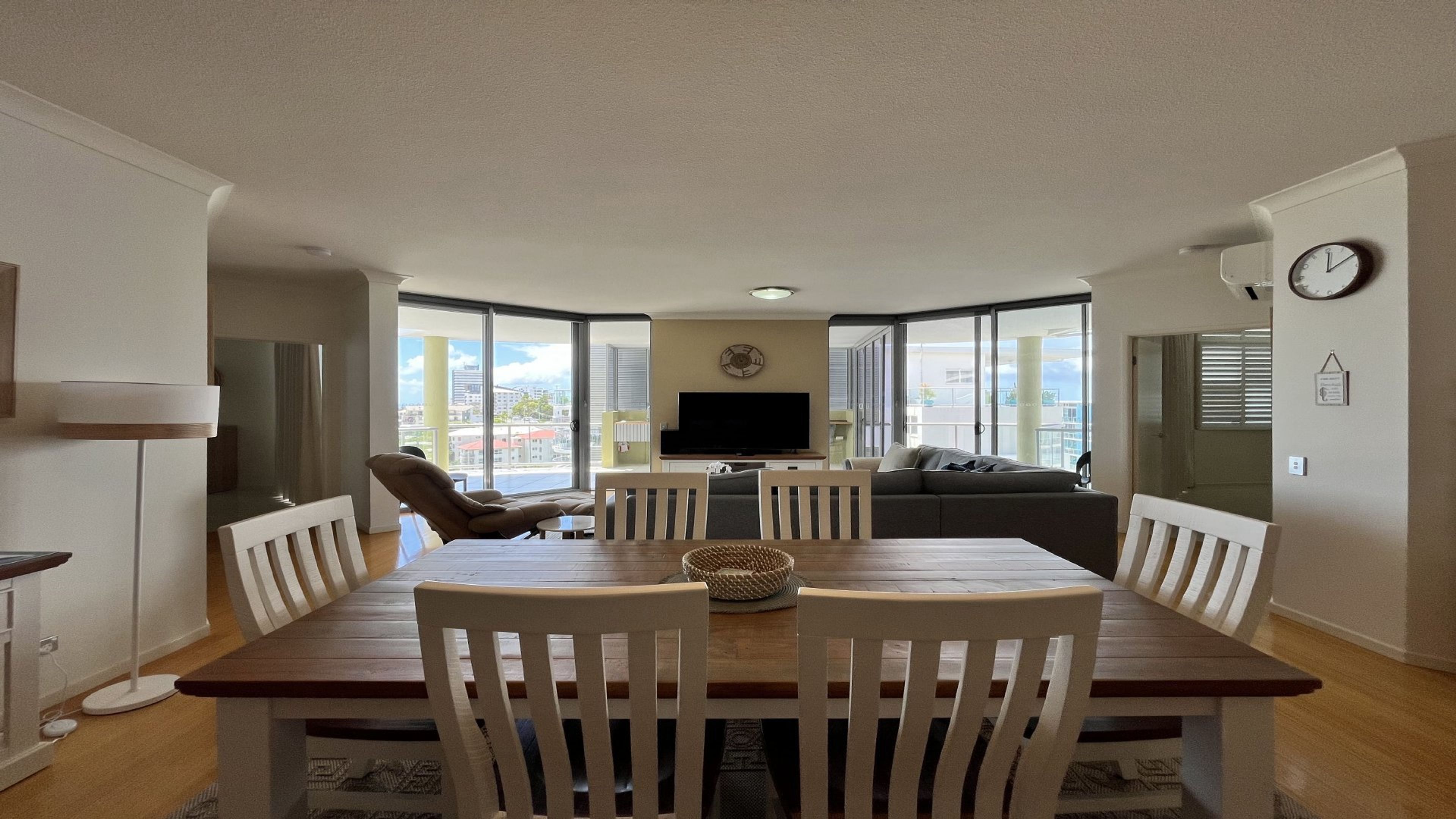 A dining area with a wooden table and chairs, a television, and a sofa.