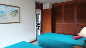 Une chambre avec deux lits, une armoire en bois et un tableau au mur.