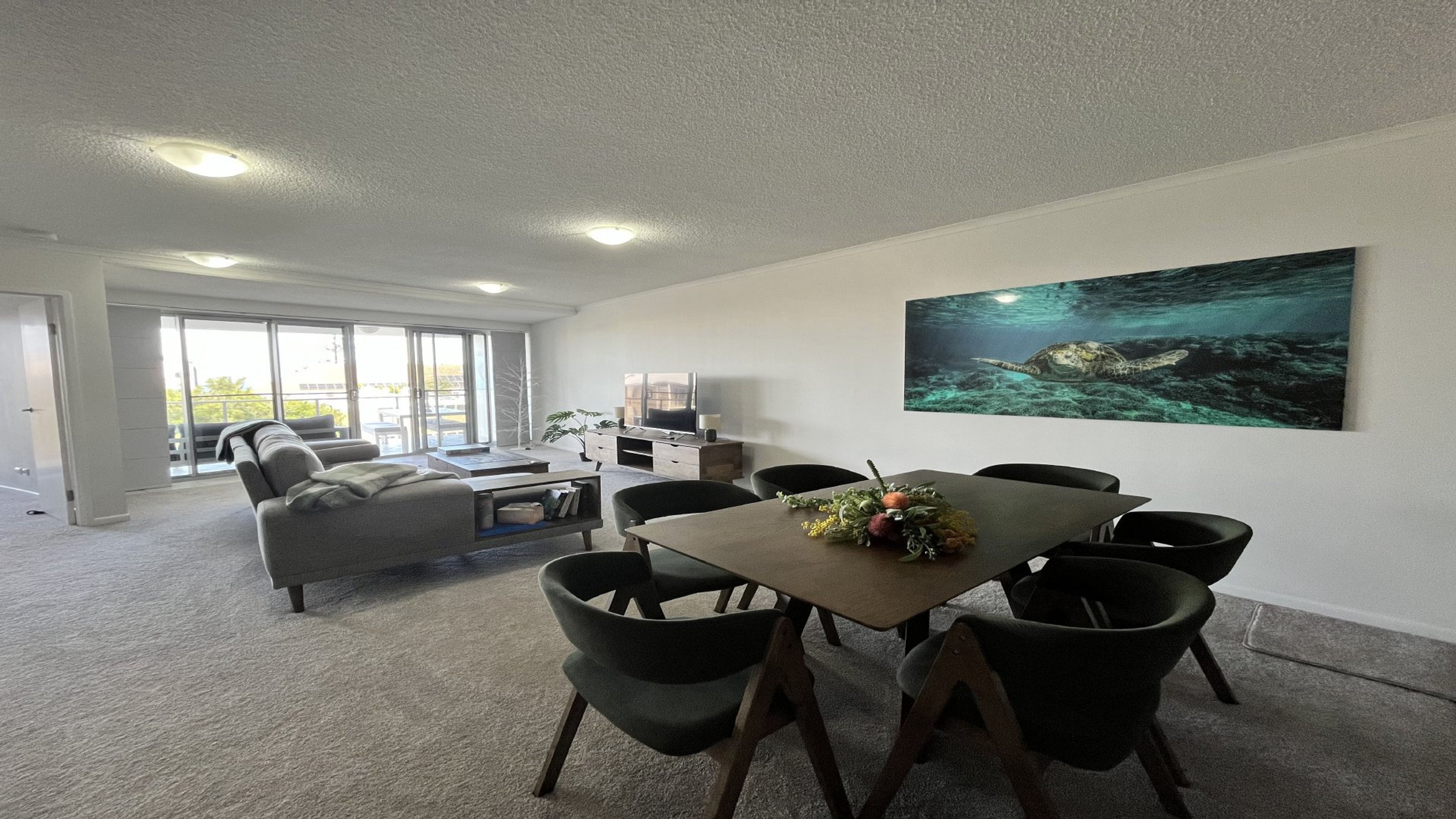 Een vergaderruimte met een tafel, stoelen, een bank en een televisie.