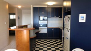A compact kitchen with dark cabinets, a checkered floor, and a wooden counter.