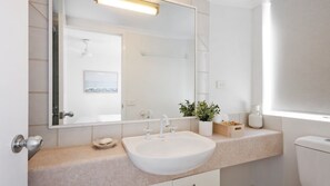 A bathroom with a white sink, a mirror, a towel rack, a potted plant, and a toilet. - Centrepoint 31 Ocean Views, Walk To Bulcock Beach (Caloundra)